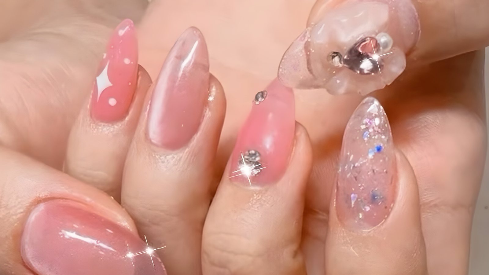 Pink jelly almond nails with crystal stones and a 3D bow charm